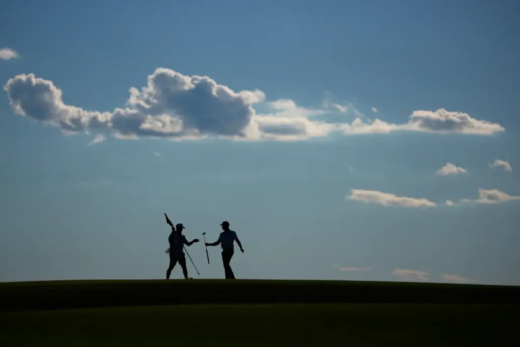Wyndham Clark hands his club to his caddie on the...