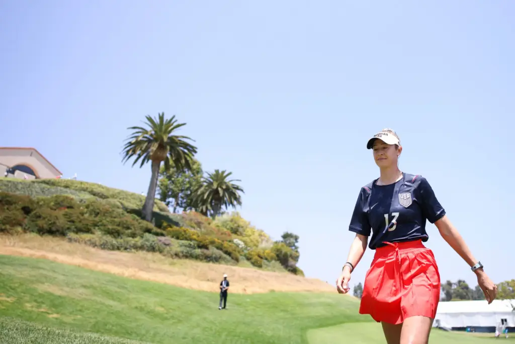 Nelly Korda, wearing a U.S soccer jersey, walks to the...