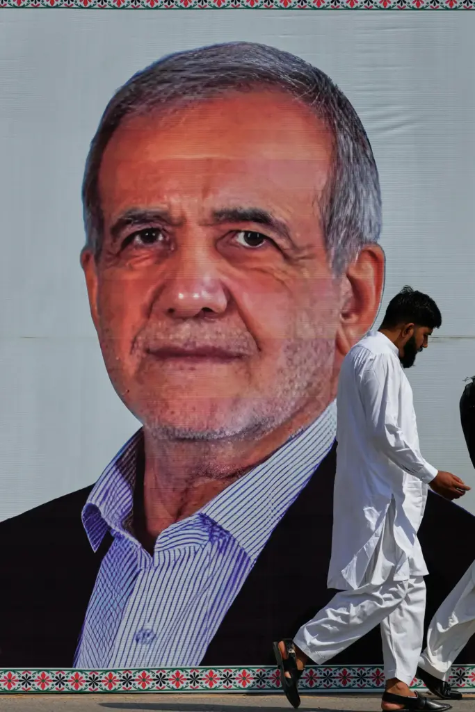 A man walks past a welcoming billboard featuring Iranian President Masoud Pezeshkian.