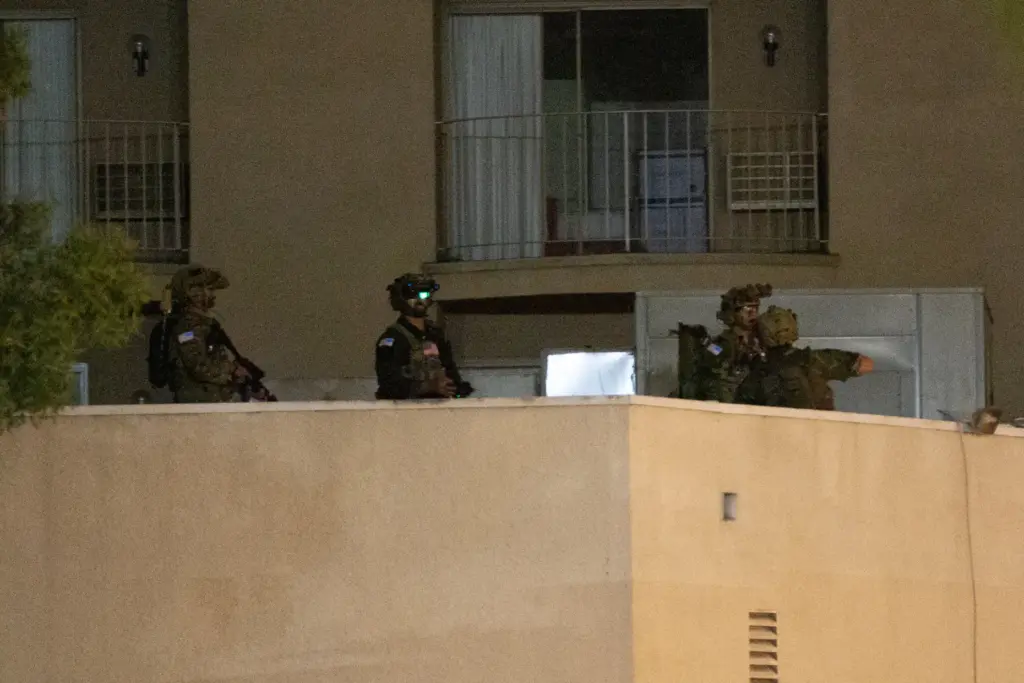 A group of soldiers stand on a rooftop during a...