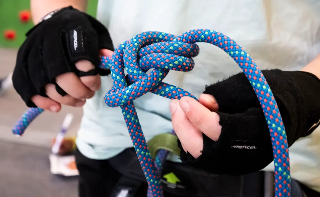 A camper practices tying into his harness during Rock Climbing...