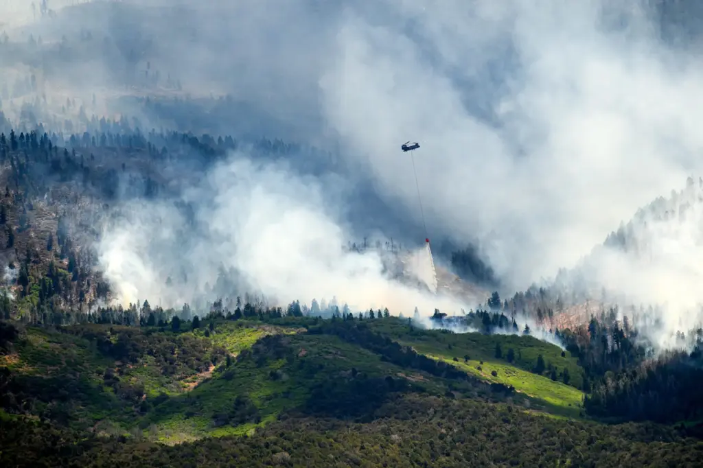 A helicopter drops water on the Cottonwood Fire burning near...