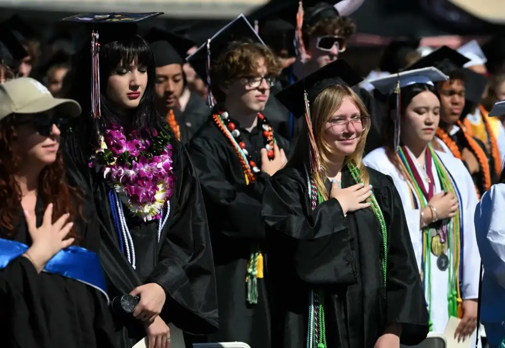 Graduates stand for the National Anthem during the Huntington Beach...