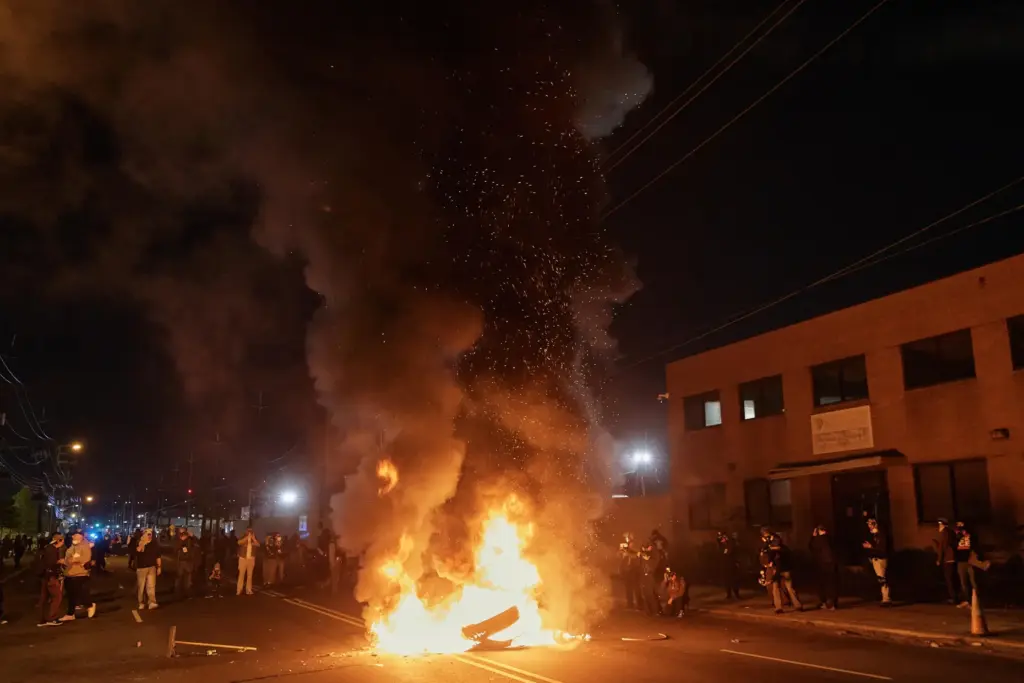 People watch a burning barricade near the Delaney Hall detention center.