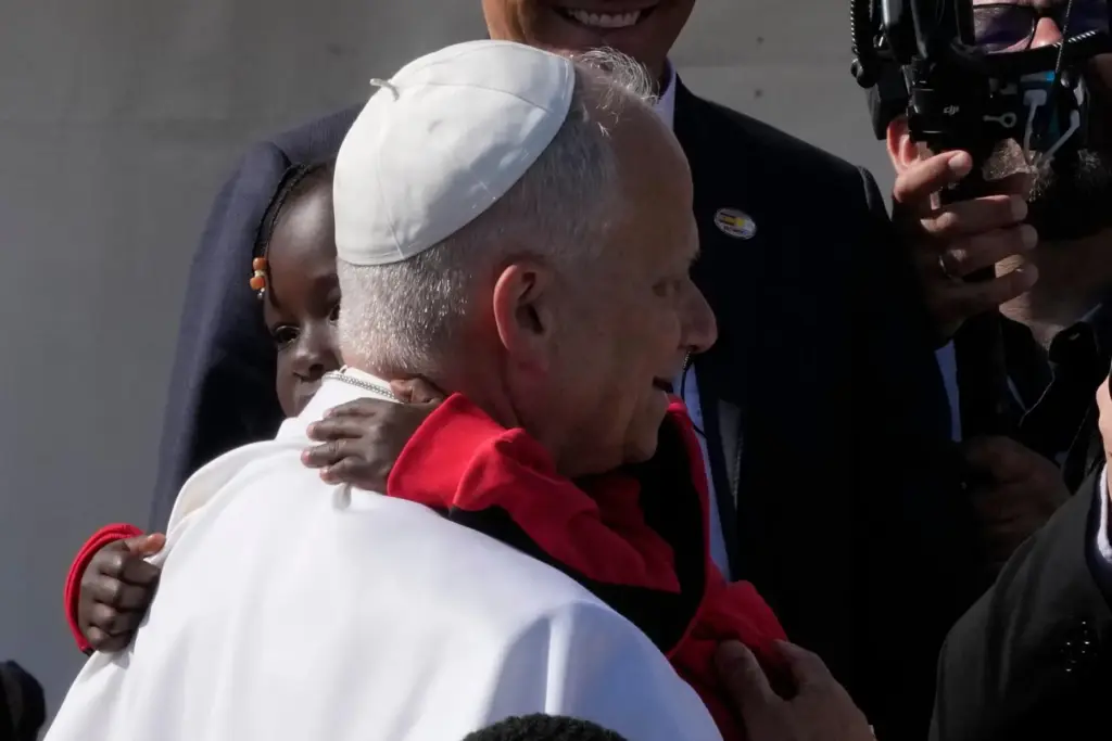 Pope Leo XIV hugs a child during a meeting with migrants at the 'Las Raices' center.