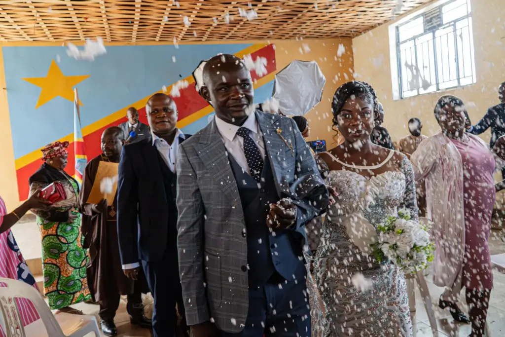 A newly married couple walks down the aisle as guests shower them with confetti.