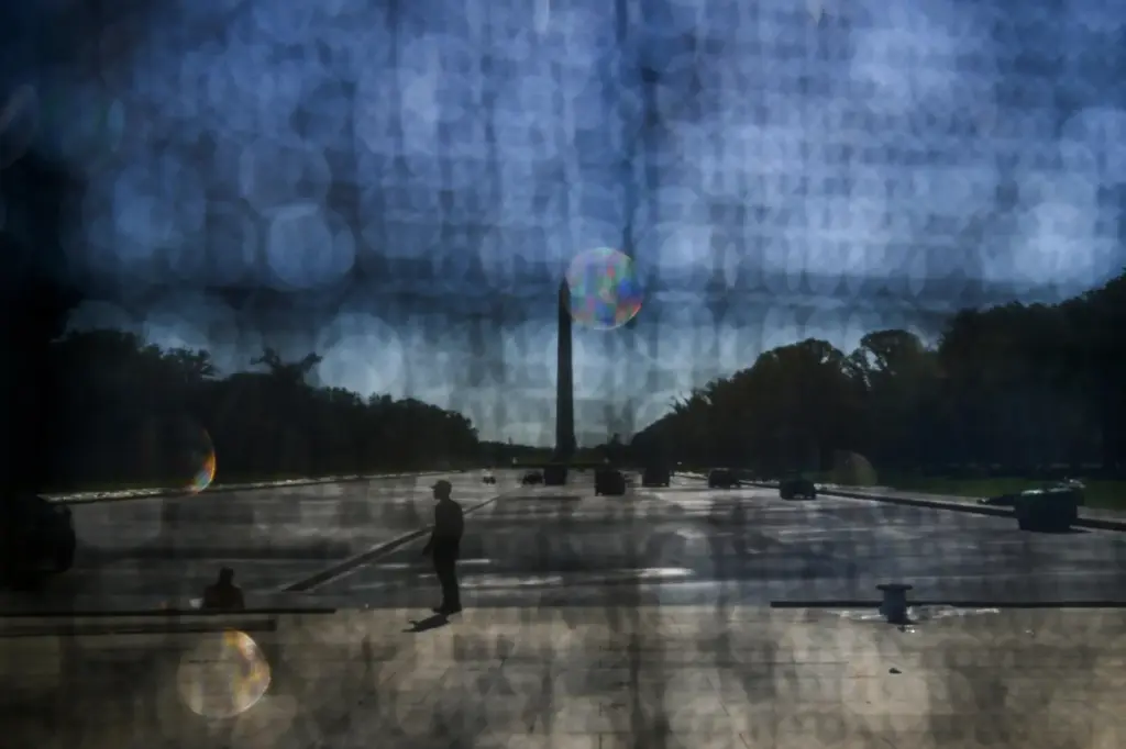 The Washington Monument is seen through a tarp as work...