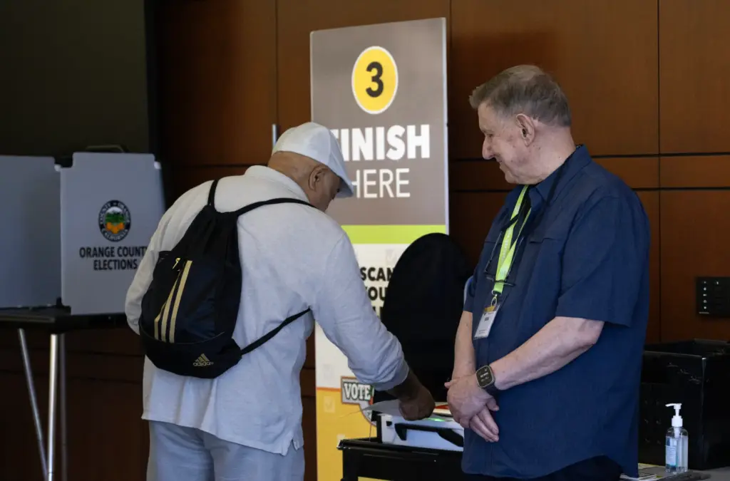 A poll worker helps a man finish the voting process...