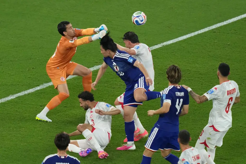 Tunisia goalkeeper Aymen Dahmen blocks a charge by Japan’s Ayase...