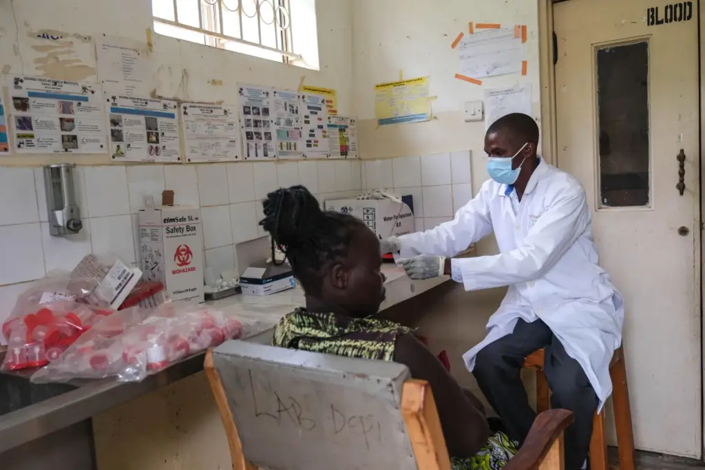 A laboratory technician works with a patient at Kikyo Health Centre IV.
