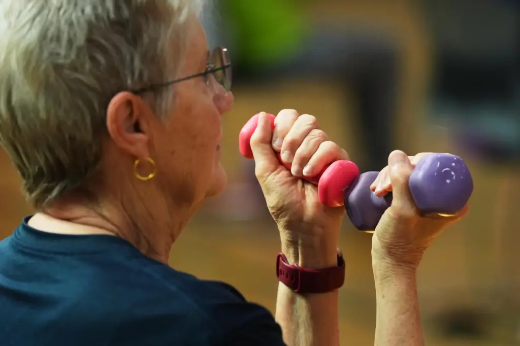 A participant uses light weights during a class for older adults.