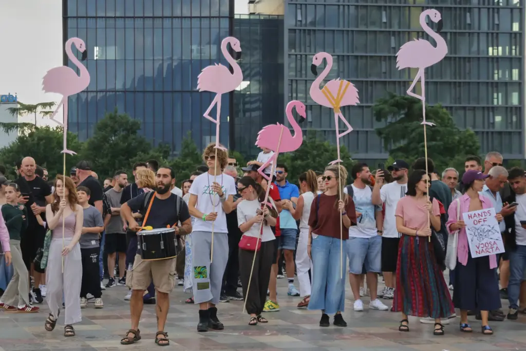 Protesters hold pink flamingo cutouts during a demonstration in Tirana,...
