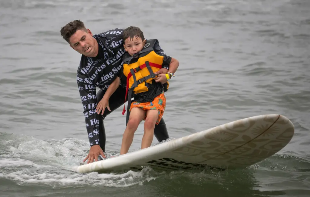 Surfers Healing volunteer Richard Bradbury steadies the board as he...