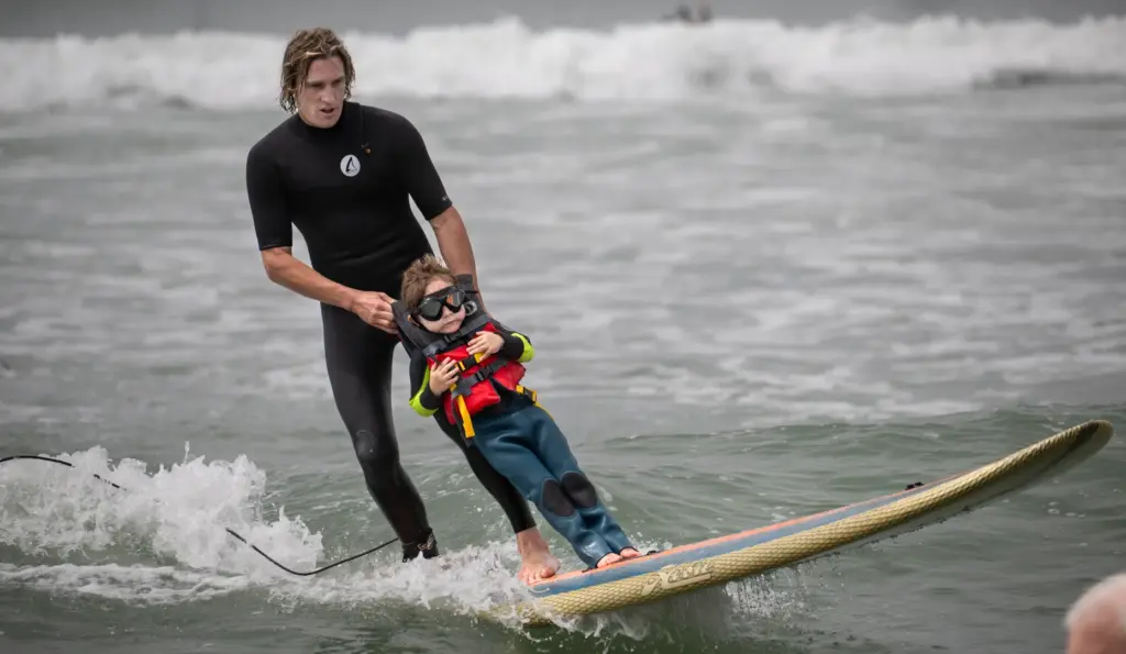Three-year-old Ford Uytengsu cruises into the shore with Surfers Healing...