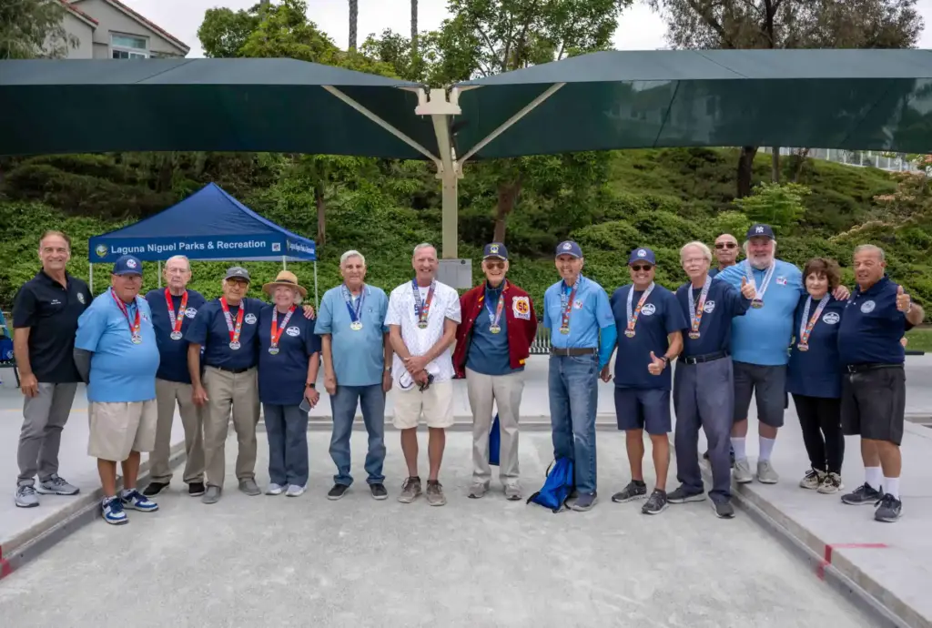 Three teams of bocce ball players stand together with their...
