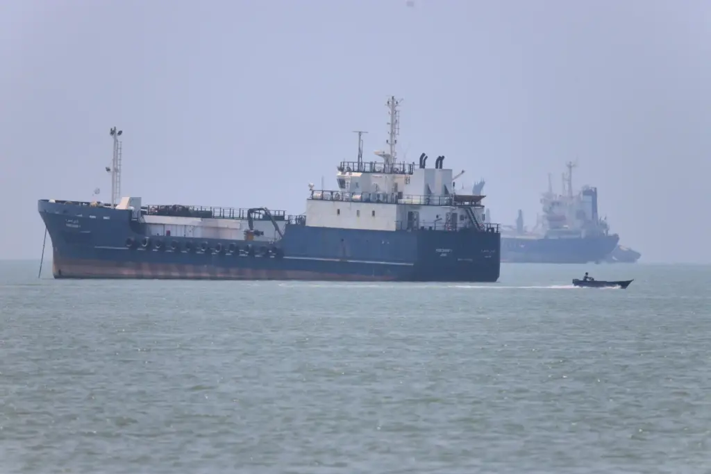 A small motorboat passes anchored vessels in the Strait of Hormuz.