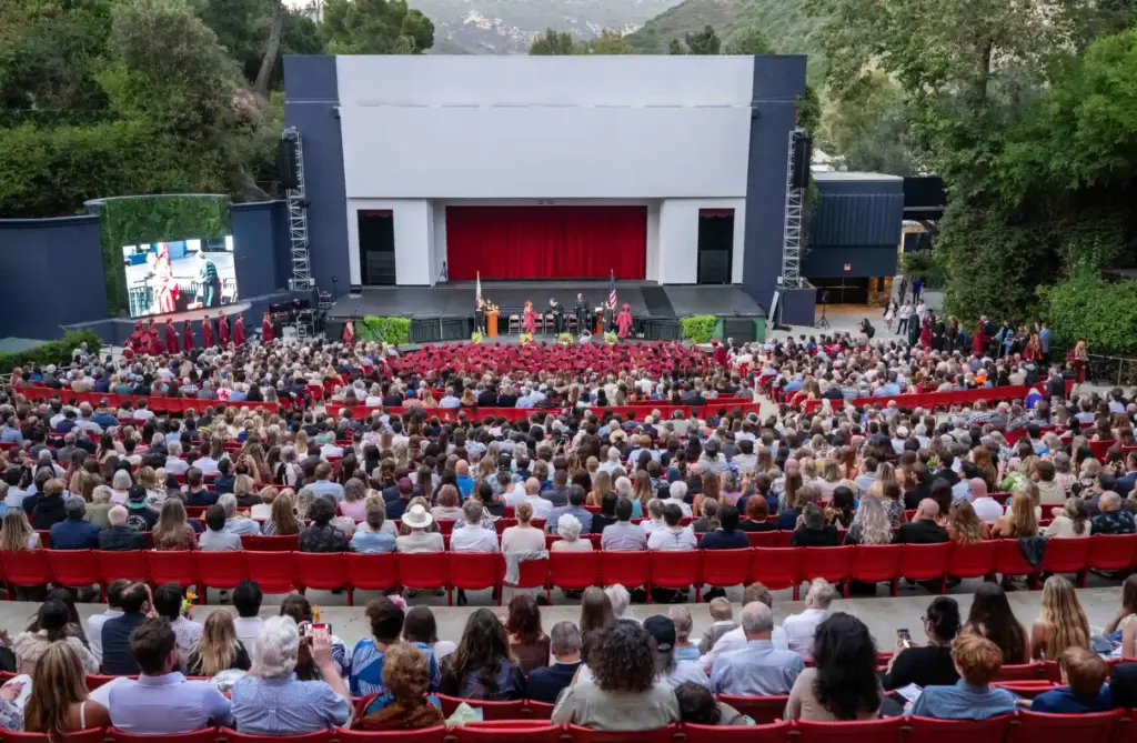 Graduates line up to walk across stage and accept their...