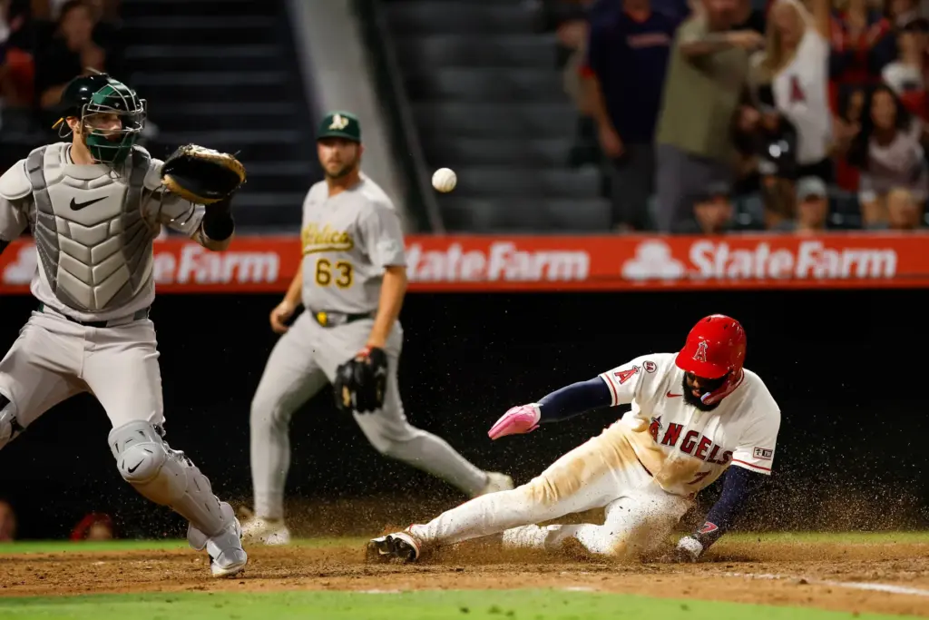 Angels’ Jo Adell (7) slides into home plate to score...