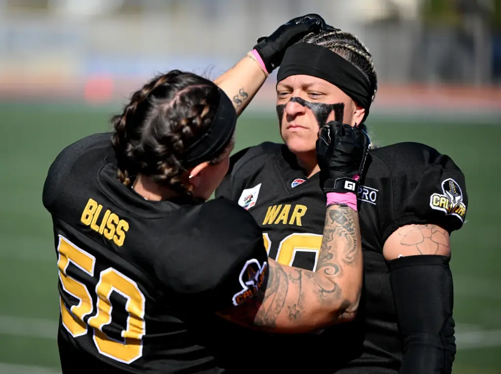 Cali War linebacker Joann Bliss puts face paint on Jennifer...