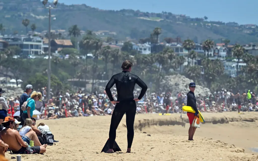 A lifeguards keep an eye on bodyboarders as beachgoers watch...