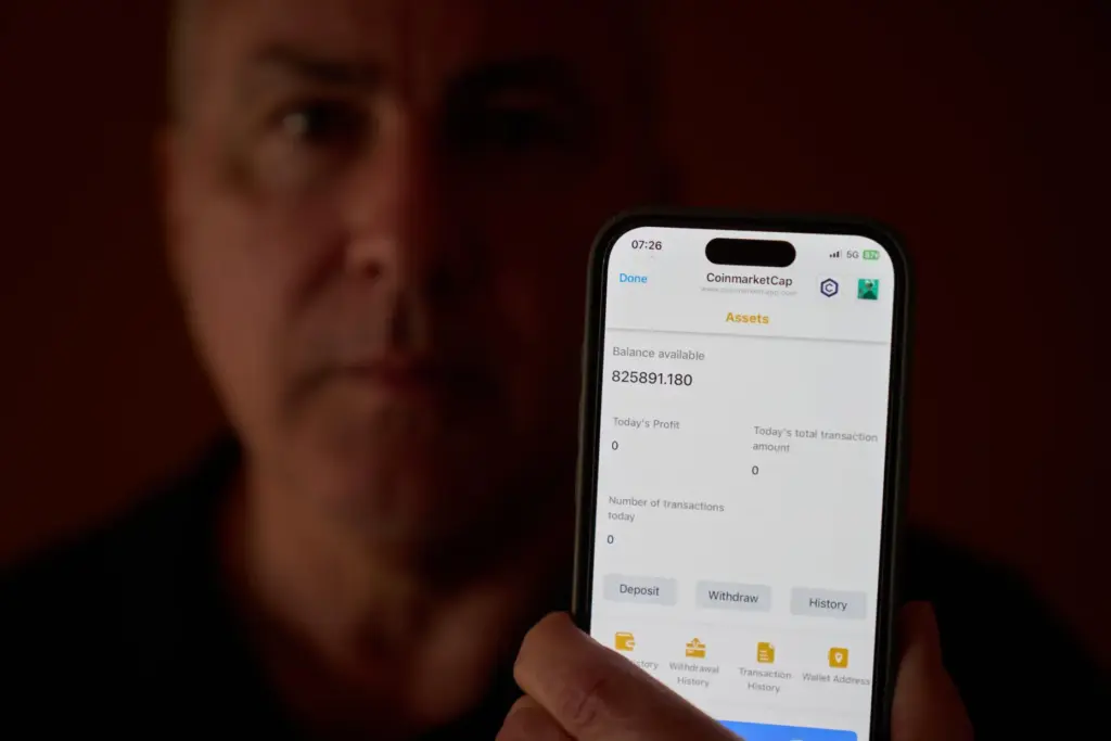 Chris Colocousis holds up a screenshot of the fake app where he invested his savings.