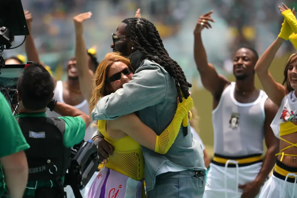 Shakira and Burna Boy embrace during the opening ceremony before...
