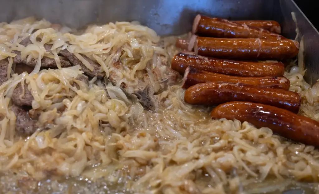 Sausages, sauteed onions, and pork chops sizzle on the grill...