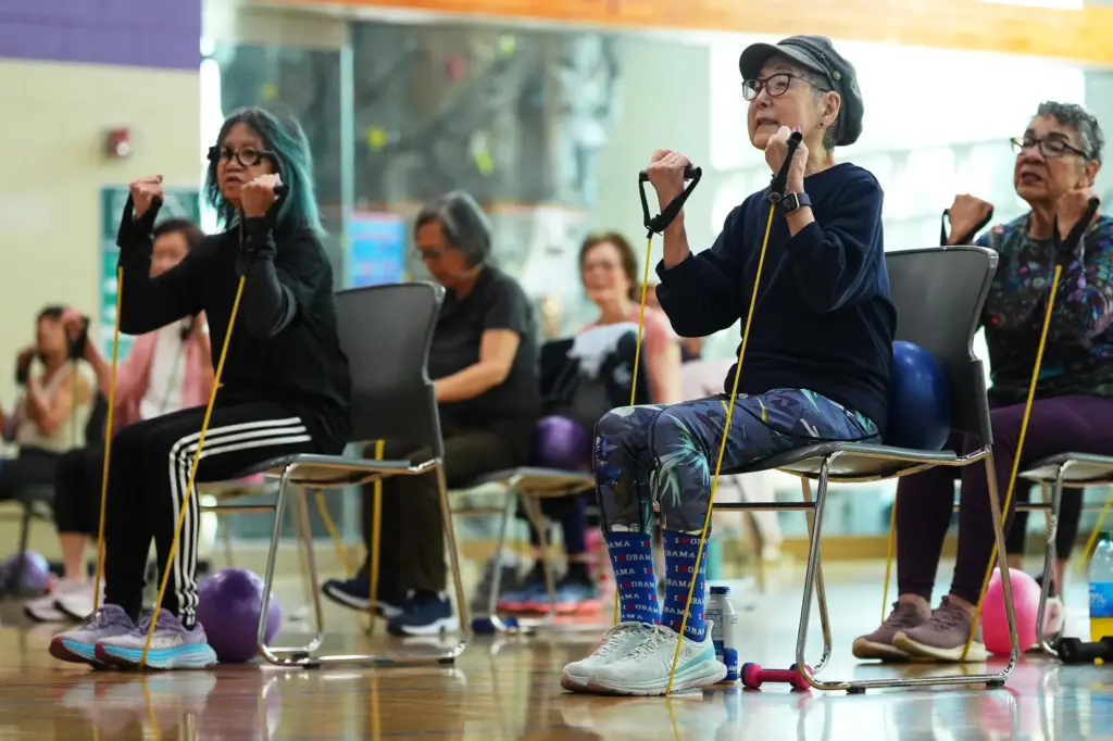 Ann Kashiwa, 91, right, uses an exercise band while taking a class for older adults.