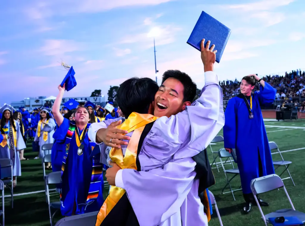 Jason Chun, center, hugs a fellow graduate following the Valencia...