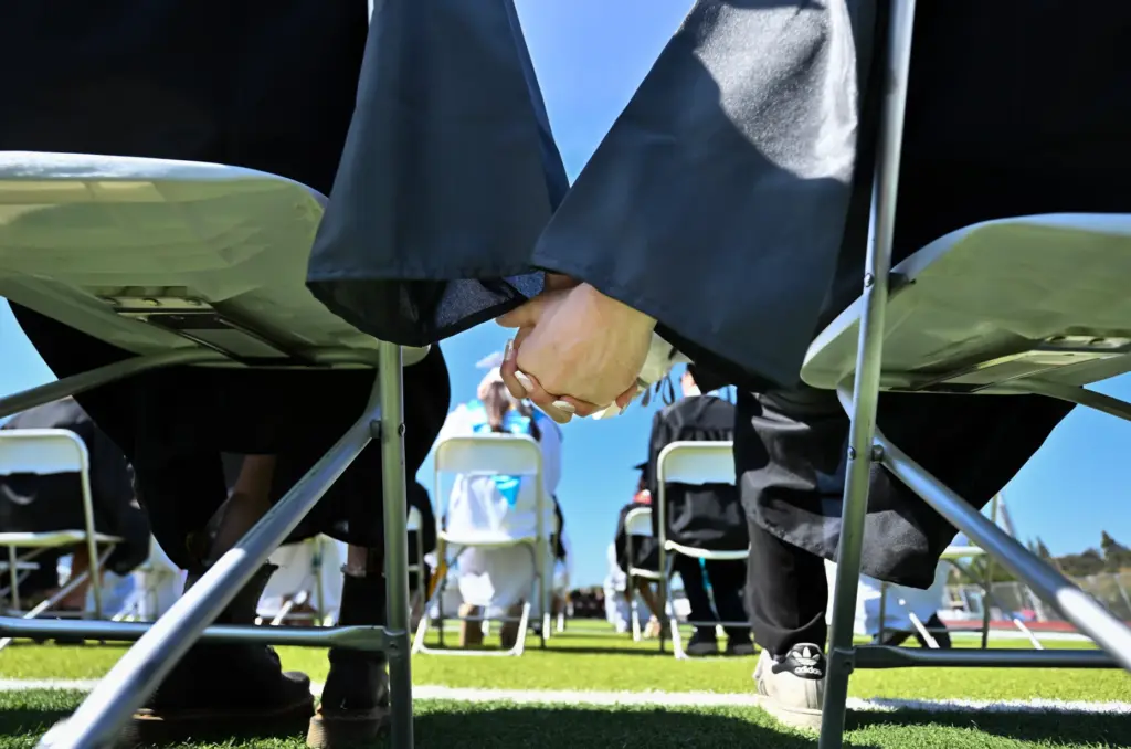 Graduates William Marion Nelson and Rowan Aleta Donald hold hands...