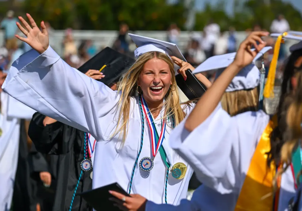Graduate Sophia Dickson greets friends after getting their diplomas during...