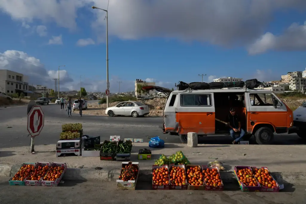 FILE – A Palestinian street vendor waits for customers while...