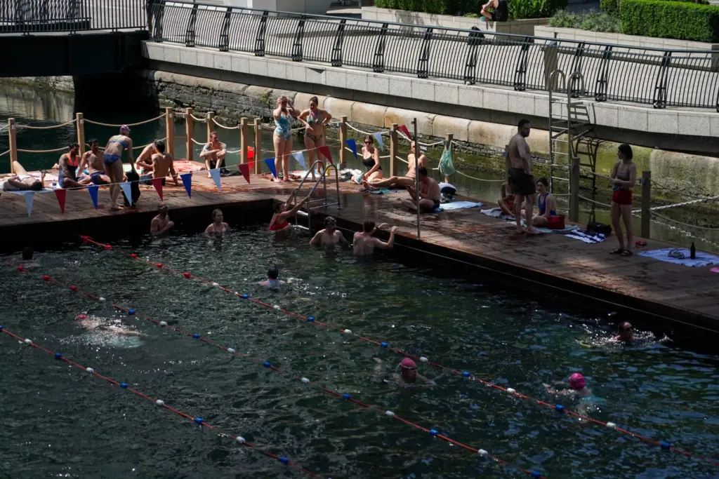 People swim in an outdoor swimming pool in London, Tuesday,...