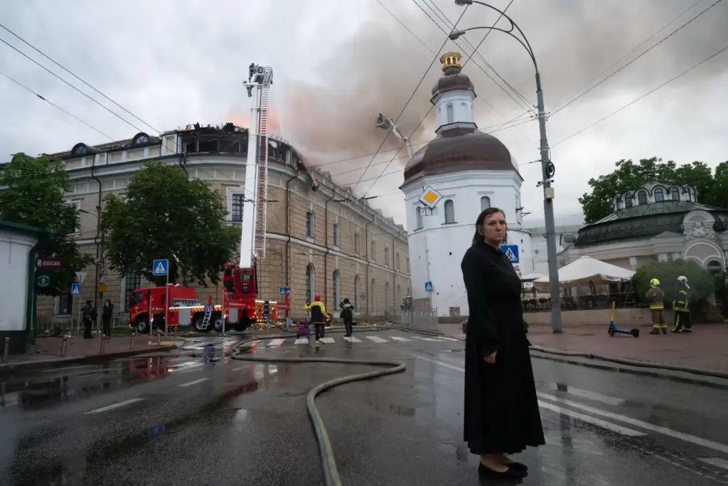 A woman stands at a street near a damaged building following an overnight Russian attack.