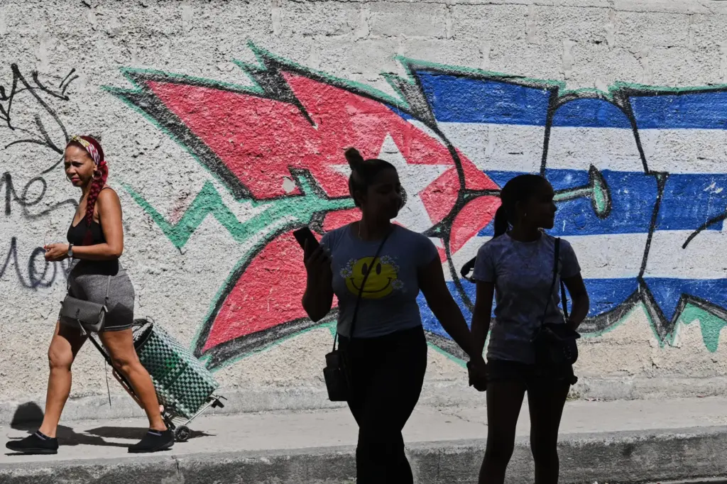 People walk past graffiti in the colors of the Cuban...
