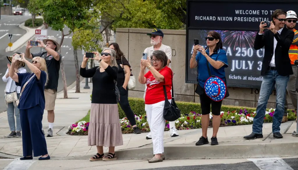 Visitors take photos as the presidential helicopter leaves the Nixon...