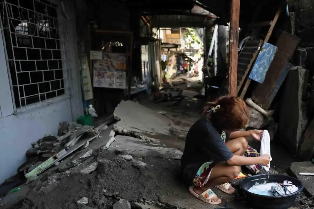 A woman washes clothes along a damaged pathway in General...
