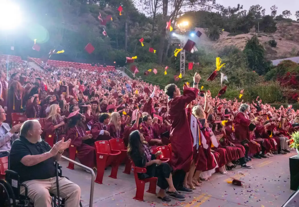 Graduates toss their caps in the air in celebration at...
