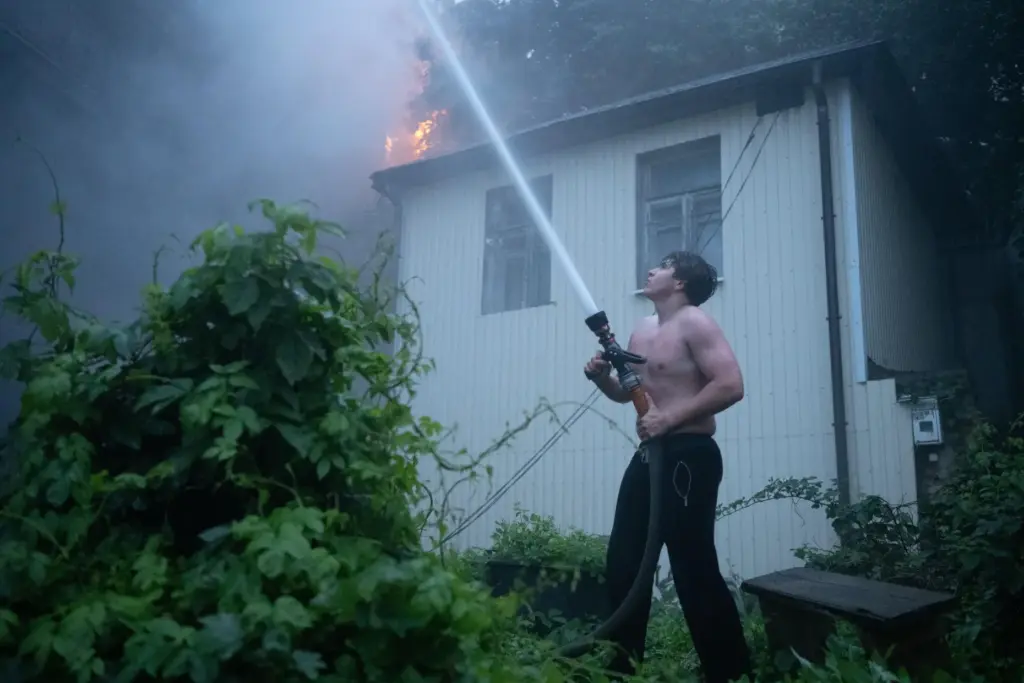A local resident uses a firehose to extinguish a fire in Kyiv.