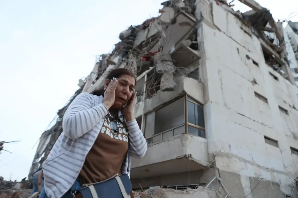 A woman walks past a building damaged during an earthquake...
