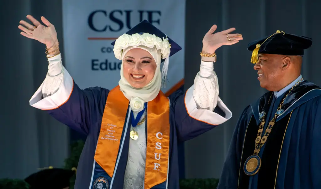 Zena Rasheed waves during CSUF College of Educationâs graduation ceremony...