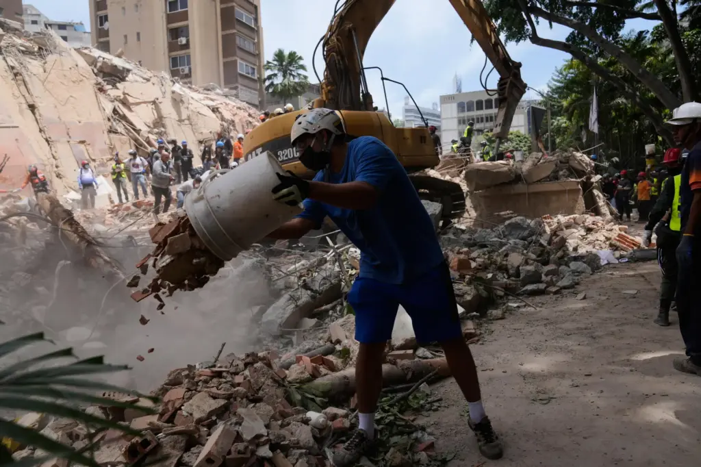 Residents help to remove rubble from a collapsed building in...