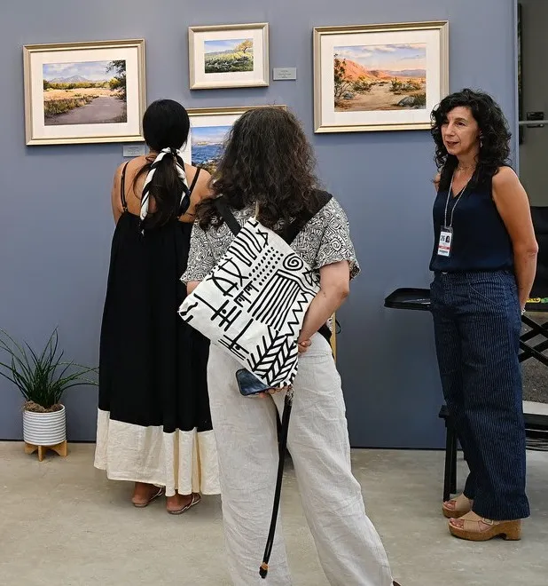 Watercolorist Becky Ryan, right, speaks to festivalgoers about her landscapes...