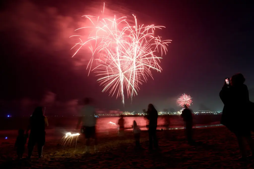 Children play with sparklers as simultaneous fireworks displays in Long...