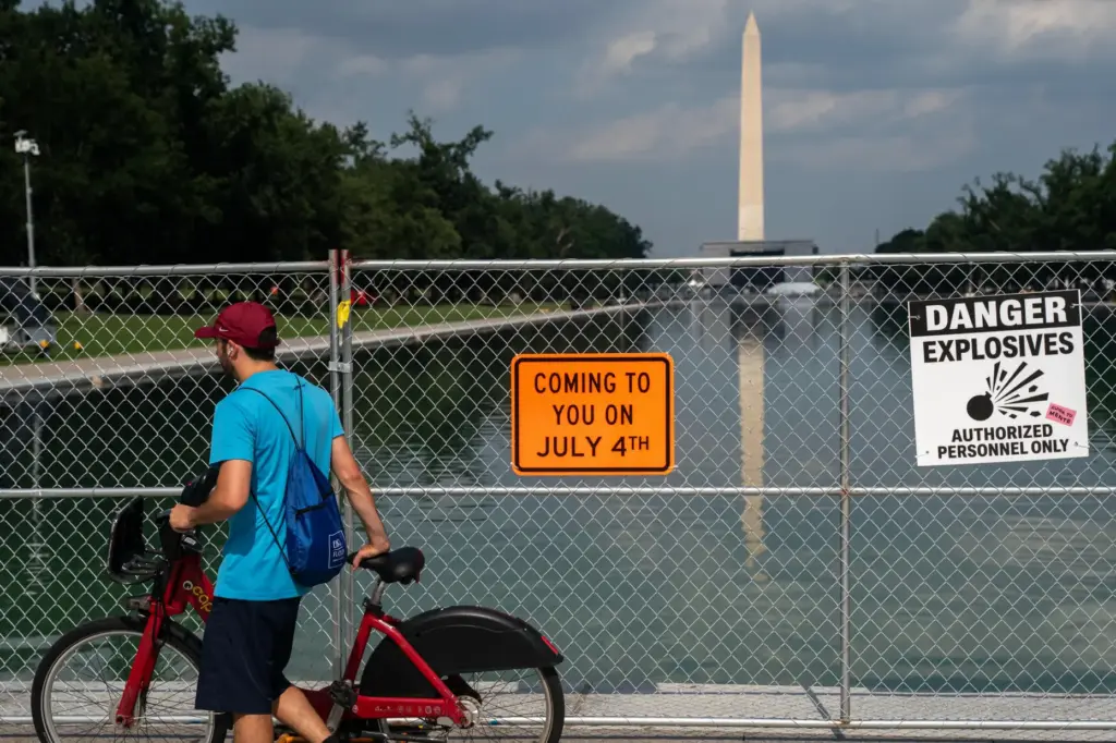 A man on a bike passes security fencing along the...