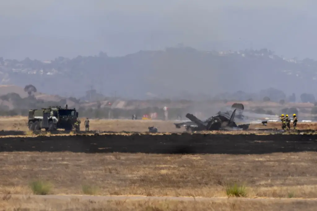 Crews work to douse a F-35 fighter jet that crashed...