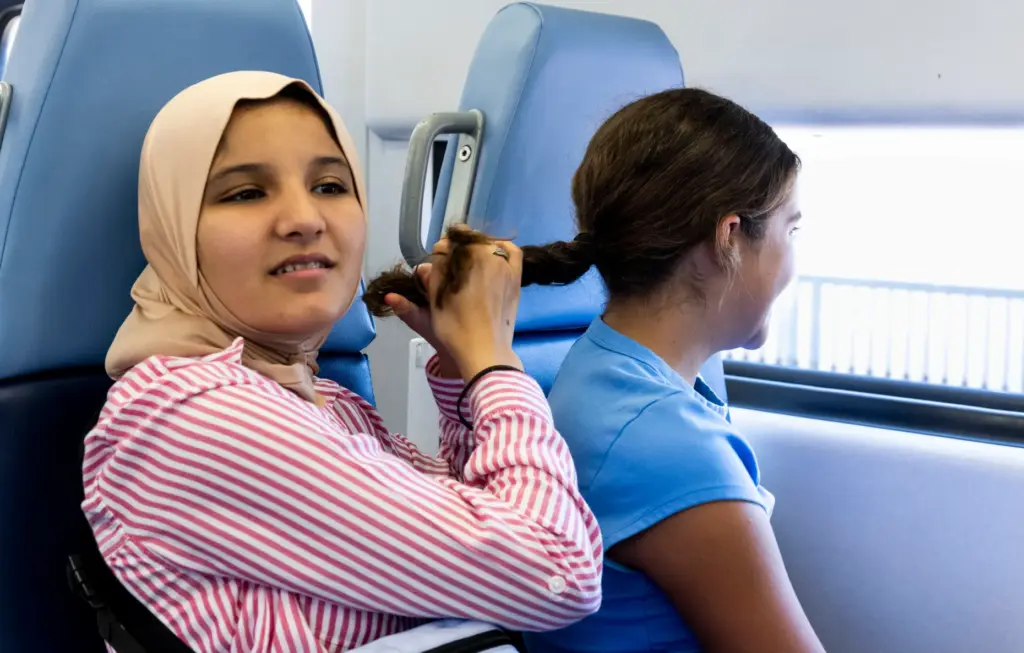 Camper Jasmine Jaber, left, braids Lora Steinmannâs hair while riding...
