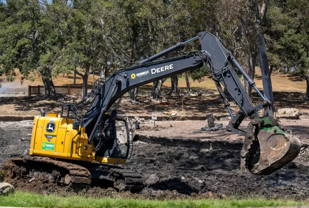 Workers use heavy equipment to grade the lower lakebed as...