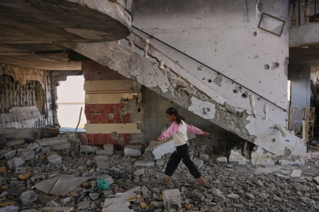 Arjwan al-Gharam walks over debris inside her home after it...