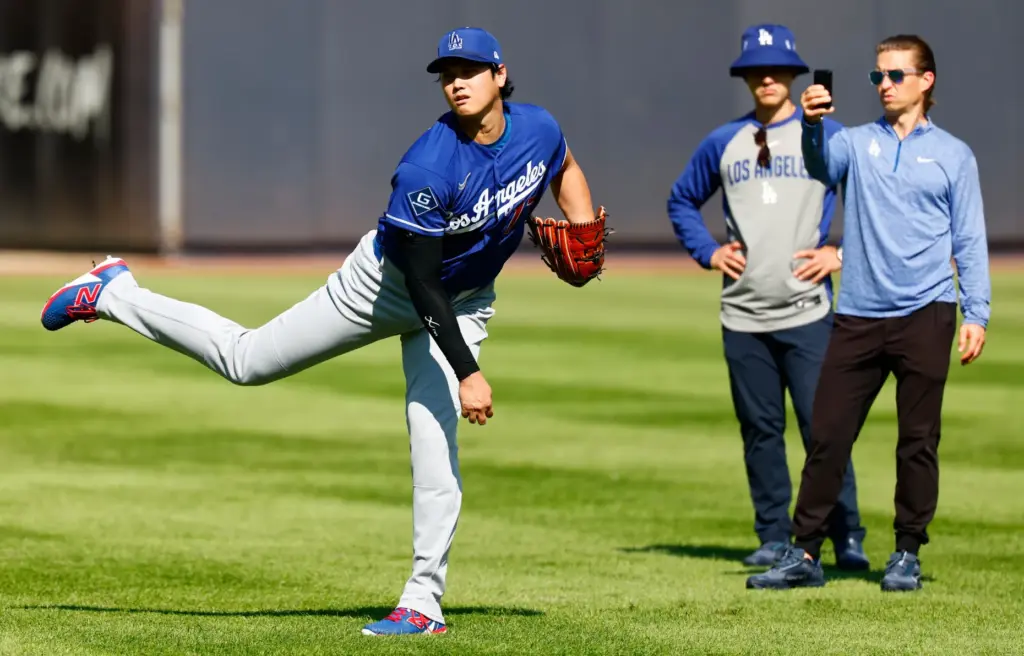 Dodgers’ Shohei Ohtani, left, throws in the outfield before the...